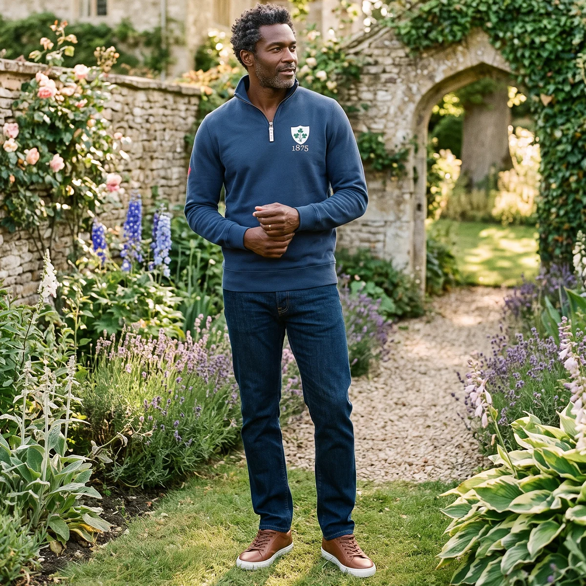 Rugby 1823 Pure Cotton Half Zip Sweatshirt A man stands confidently in a beautiful country garden next to a wall covered in flowers. He wears a Rugby 1823 Pure Cotton Half Zip Sweatshirt.